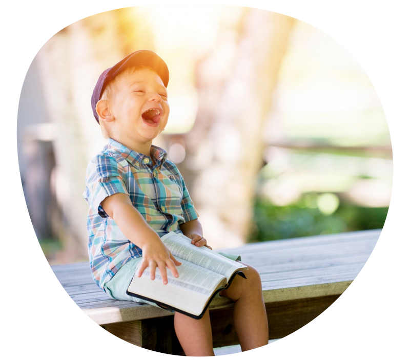 laughing-boy-blob Happy boy sitting on bench holding book